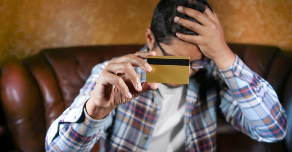 Homem preocupado com a mão na cabeça segura cartão de crédito dourado