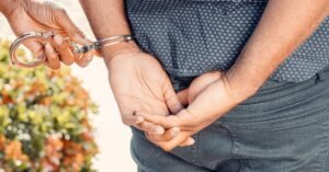 Policial algema suspeito com as mãos para trás durante abordagem