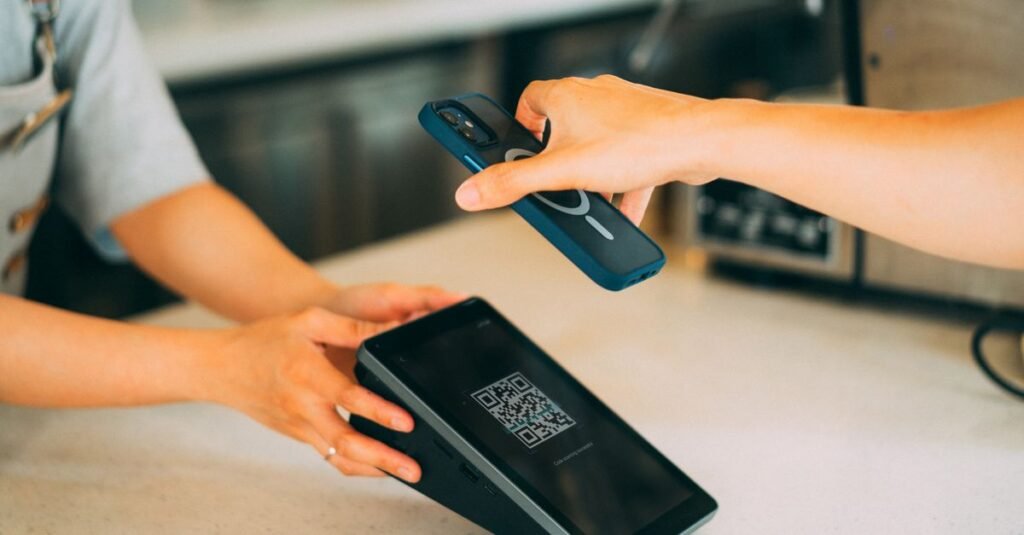 Cliente aproxima celular de maquininha para pagar com QR code