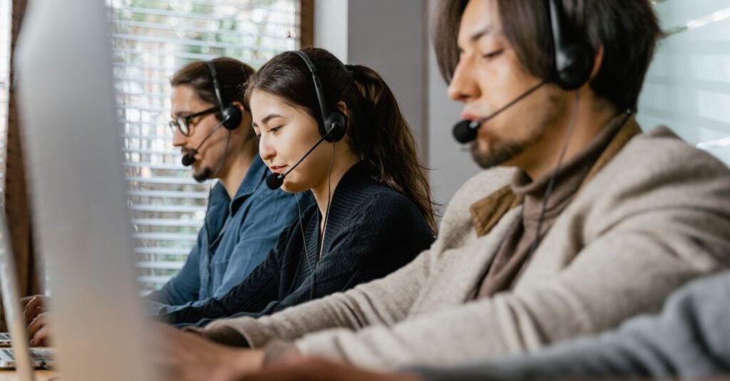 Equipe de operadores com fones de ouvido trabalhando em central de atendimento telefônico