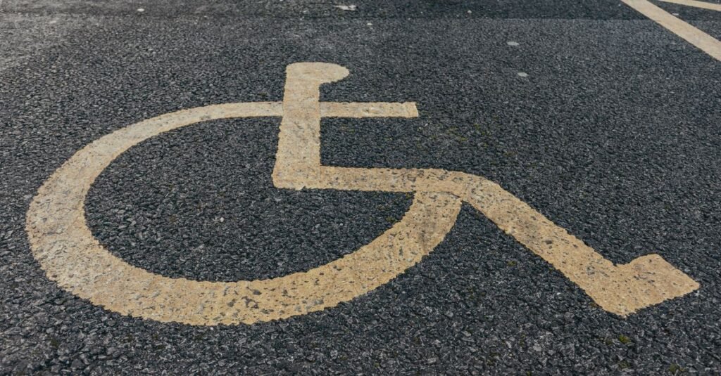 Símbolo internacional de acessibilidade pintado em amarelo sobre asfalto