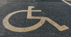 Símbolo internacional de acessibilidade pintado em amarelo sobre asfalto