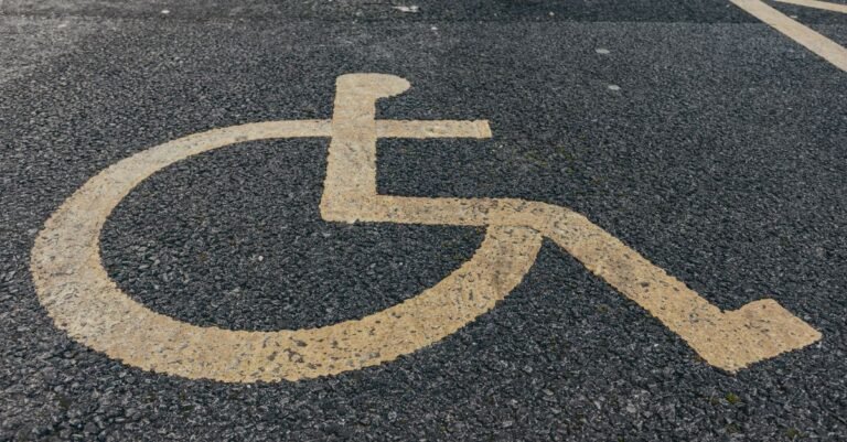 Símbolo internacional de acessibilidade pintado em amarelo sobre asfalto