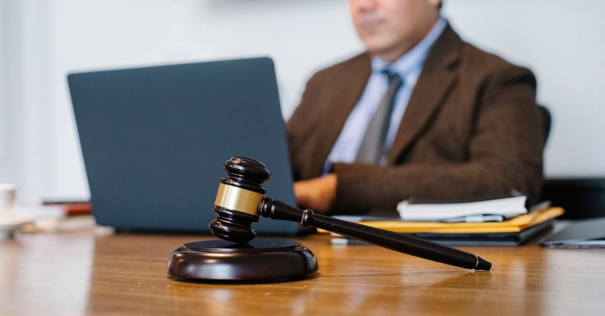 Martelo de juiz sobre mesa de madeira em ambiente de tribunal