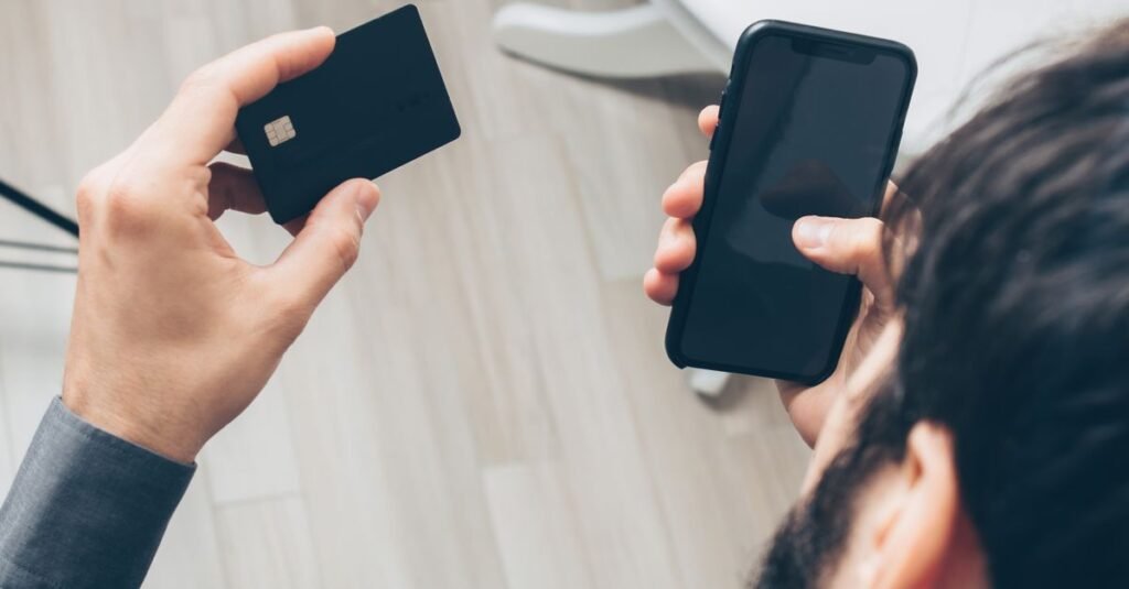 Pessoa consulta o celular com cartão na mão; restituição do lote especial do IR cai via Pix