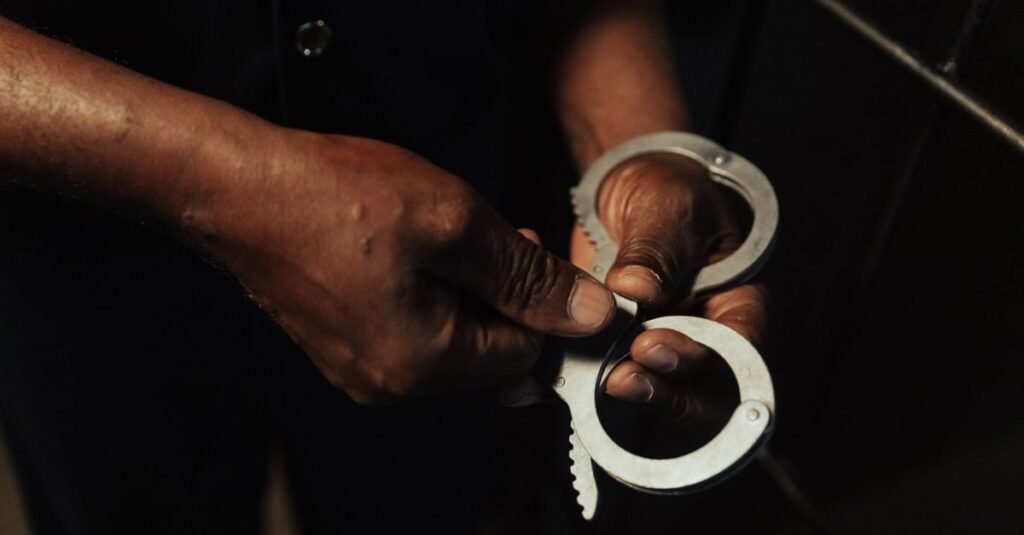 Algemas abertas nas mãos de um agente, em fundo escuro