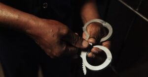 Algemas abertas nas mãos de um agente, em fundo escuro