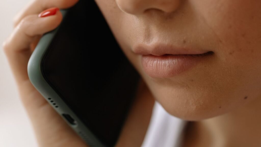 Mulher segura celular junto ao ouvido durante ligação telefônica