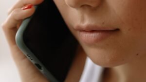 Mulher segura celular junto ao ouvido durante ligação telefônica