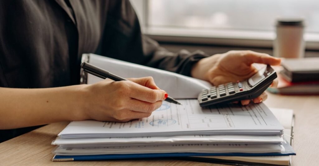 Pessoa usa calculadora sobre documentos financeiros