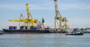 Navio cargueiro com contêineres atracado em porto com guindastes