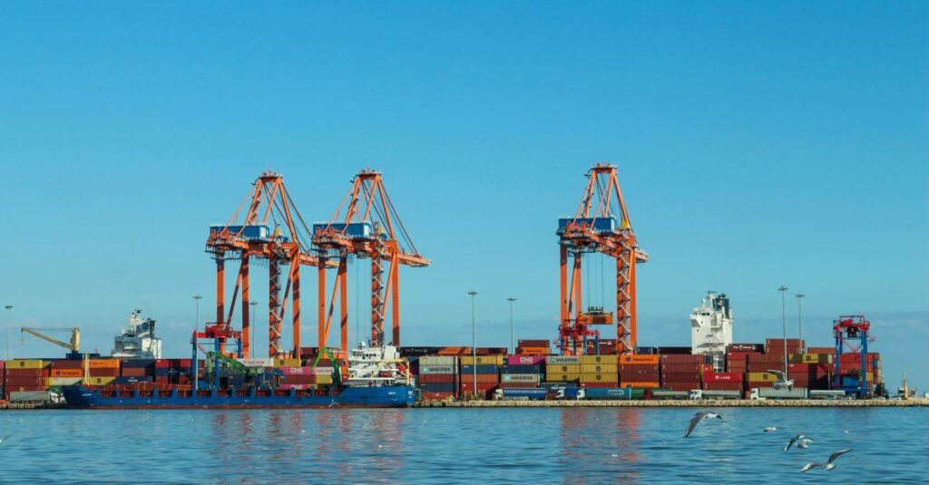 Guindastes e navios movimentam contêineres em porto