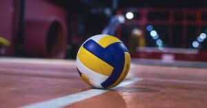 Bola de vôlei azul, amarela e branca sobre quadra indoor