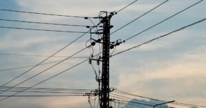 Poste de energia com fiação elétrica em silhueta contra o céu no fim da tarde