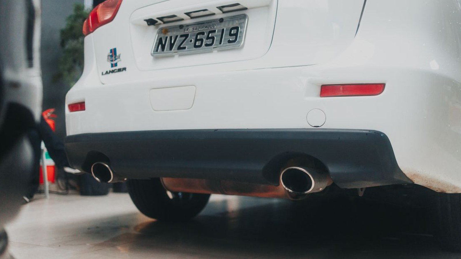 Traseira e parachoque de carro branco estacionado, com placa brasileira