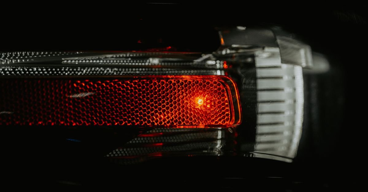 Detalhe da lanterna traseira acesa de um carro em fundo escuro