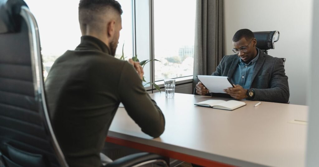 Dois profissionais sentados frente a frente durante entrevista de emprego em escritório