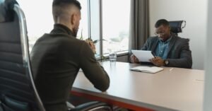 Dois profissionais sentados frente a frente durante entrevista de emprego em escritório