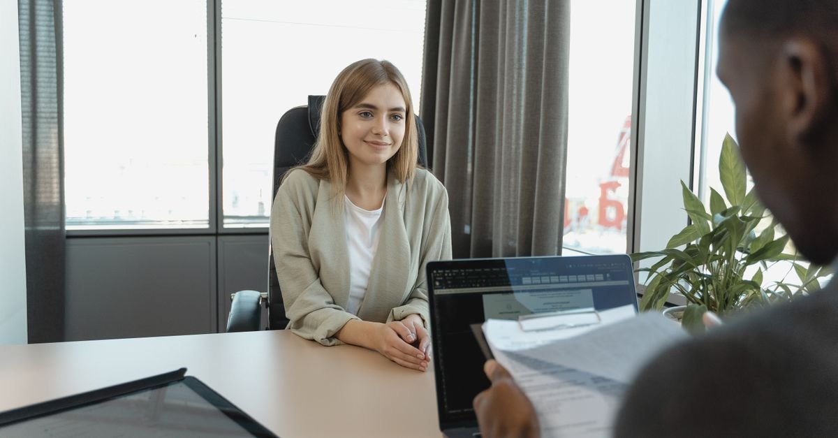 Candidata sentada diante de recrutadores durante entrevista de emprego em escritório