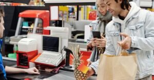 Operador de caixa atende clientes em checkout de supermercado