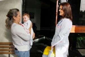 Profissional de saúde com caixa térmica recolhe leite humano na casa de uma doadora