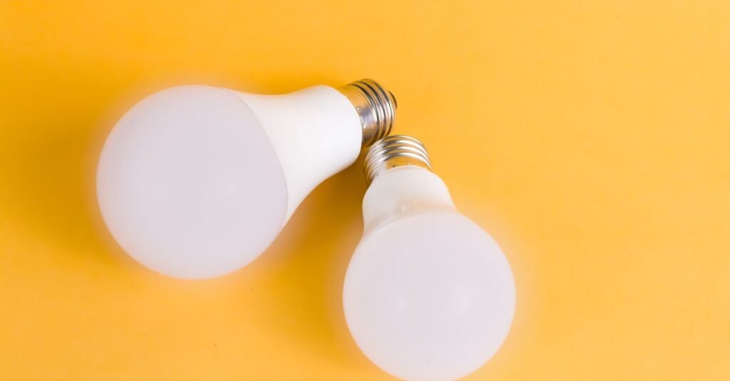 Duas lâmpadas de LED sobre fundo amarelo, representando iluminação de baixo consumo de energia
