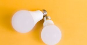Duas lâmpadas de LED sobre fundo amarelo, representando iluminação de baixo consumo de energia