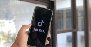 Mão segura celular com a tela de abertura do aplicativo TikTok