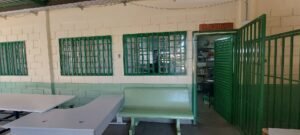 Pátio coberto de escola pública do Distrito Federal, com bancos e entrada da sala de leitura