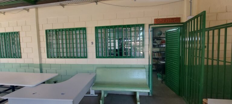 Pátio coberto de escola pública do Distrito Federal, com bancos e entrada da sala de leitura