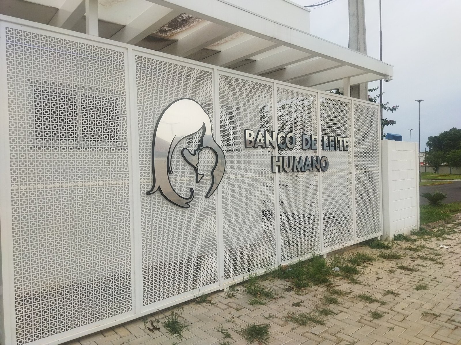 Fachada branca de uma unidade de banco de leite humano com letreiro e logotipo de mãe amamentando