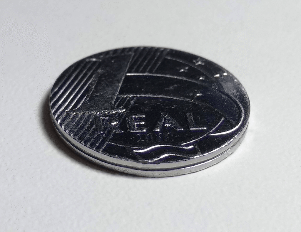 Moeda de um real em primeiro plano sobre superfície clara