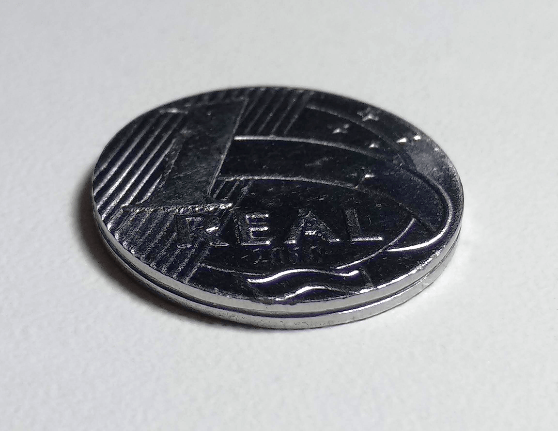 Moeda de um real em primeiro plano sobre superfície clara