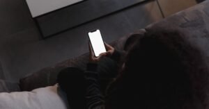 Pessoa sentada no sofa segurando celular com a tela acesa