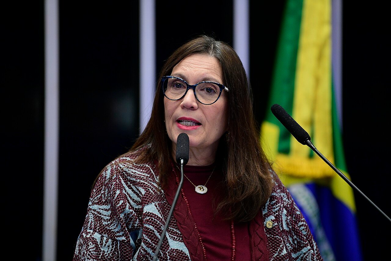 Deputada Bia Kicis discursa em tribuna com a bandeira do Brasil ao fundo
