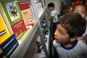 Criança observa livros expostos em estande de feira literária em Brasília