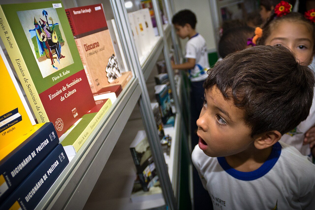 Criança observa livros expostos em estande de feira literária em Brasília