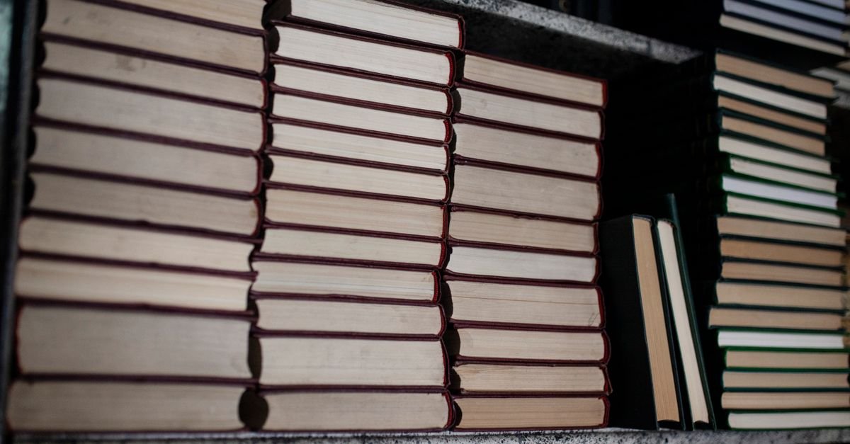 Pilhas de livros em uma estante, imagem que ilustra matéria sobre a bolsa permanência do Prouni
