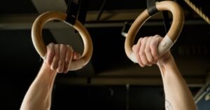 Mãos de atleta segurando argolas de ginástica artística em ginásio