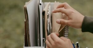 Mãos organizando documentos e envelopes de papel dentro de um arquivo