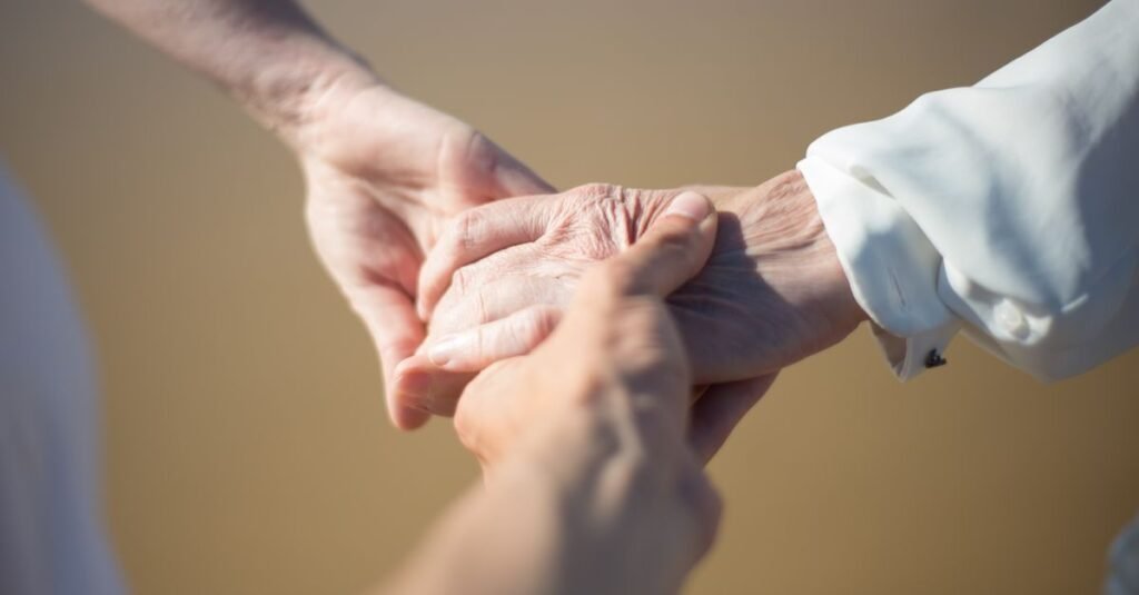 Mãos jovens segurando as mãos de uma pessoa idosa em gesto de apoio