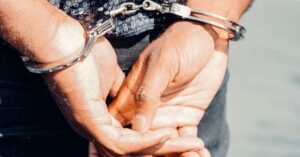 Mãos de um homem algemadas atrás das costas em uma abordagem policial