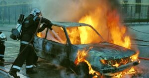 Bombeiro combate incêndio em carro tomado pelas chamas em via urbana