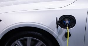 Cabo amarelo conectado a porta de recarga de um carro eletrico branco, em close