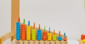 Brinquedo pedagógico de madeira com argolas coloridas e números de 1 a 10 em sala de educação infantil