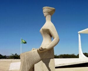 Escultura A Justiça, de Alfredo Ceschiatti, em Brasília, com a bandeira do Brasil ao fundo