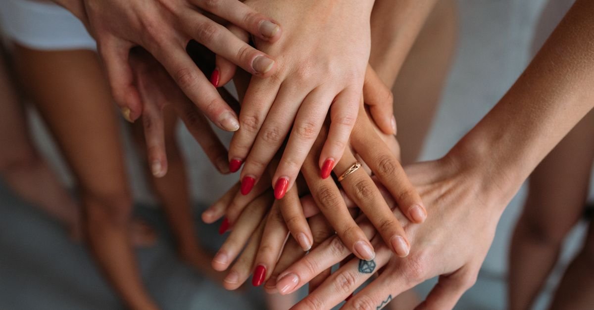 Mãos de mulheres unidas em gesto de apoio mútuo