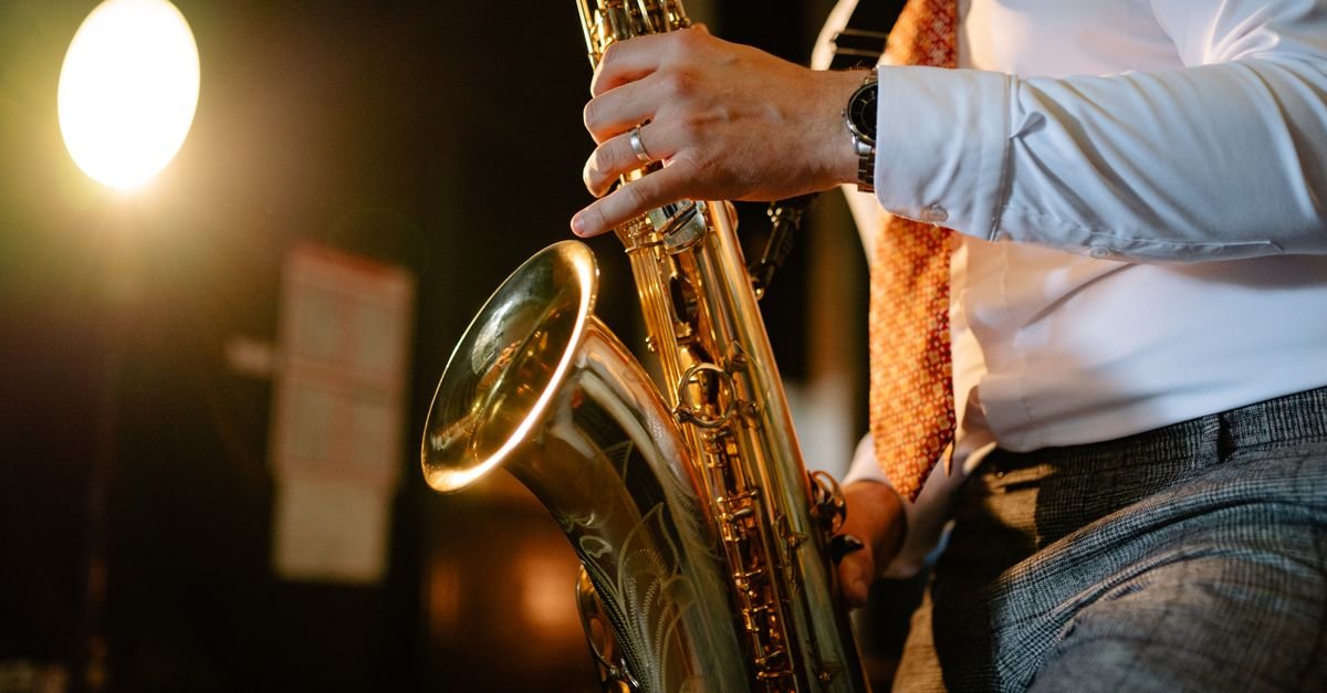 Saxofonista tocando em apresentação ao vivo, com refletor ao fundo
