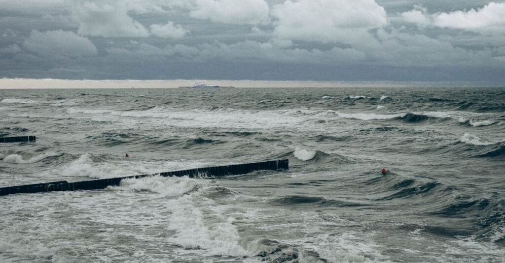 Mar agitado com ondas quebrando e ceu carregado de nuvens escuras durante temporal no litoral