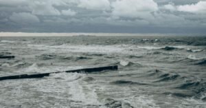 Mar agitado com ondas quebrando e ceu carregado de nuvens escuras durante temporal no litoral